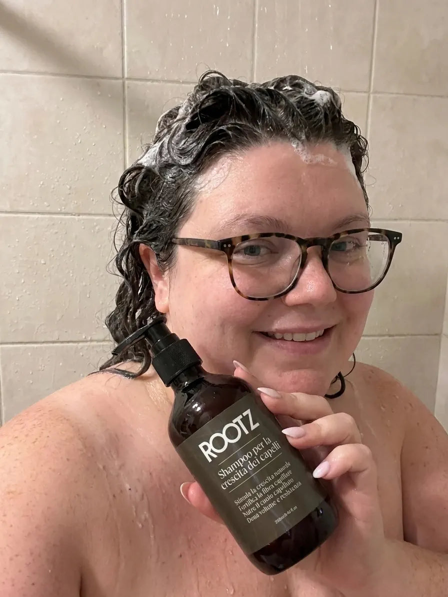 Una clienta se lava el pelo con el champú ROOTZ en la ducha, con la etiqueta del bote a la vista